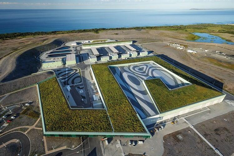 Diseño de techo verde con sistema Atlantis Edificio con techo verde y vegetación, diseñado con el sistema Atlantis para eficiencia energética y sostenibilidad.